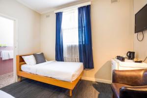 アデレードにあるエスプラネード ホテル アデレードのベッドルーム1室(ベッド1台、青いカーテン付きの窓付)