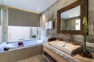 a bathroom with a large tub and a large mirror at Daun Lebar Villas in Payangan