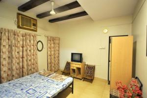 um quarto com uma cama e uma televisão em Shilaj em Dapoli