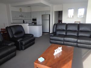 a living room with black leather furniture and a coffee table at The Beach Villa Bunbury in Bunbury