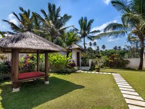 a garden with a gazebo and palm trees at Villa Candi Kecil Tiga in Ubud