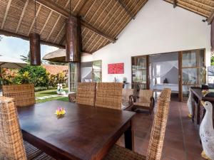 uma sala de jantar em plano aberto com uma mesa de madeira e cadeiras em Villa Candi Kecil Tiga em Ubud