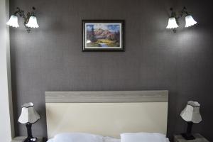 a bedroom with a bed with two lights above it at Hotel Orbi Plaza in Batumi