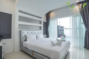 a bedroom with a white bed with a large window at Le Leaf Valley Hua Hin 29 in Hua Hin