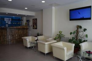 a waiting room with white chairs and a flat screen tv at Hotel Florentina in Constanţa