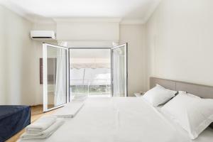 a white bedroom with a large bed and a large window at Kolonaki Square Apartment in Athens