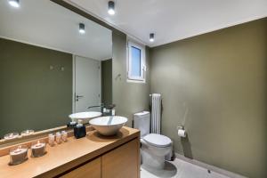 a bathroom with a sink and a toilet and a mirror at Kolonaki Square Apartment in Athens
