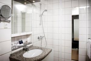 a bathroom with a shower, sink, and mirror at Munkebjerg Hotel in Vejle