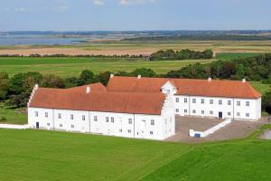 Danhostel Vitskøl Kloster في Ranum: مبنى ابيض كبير بسقف احمر في ميدان