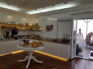 a woman standing in a kitchen with a table at Apollon Boutique Hotel in Parikia