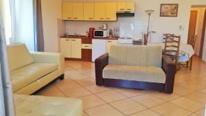 a living room with two chairs and a kitchen at Obala Apartment & Studios in Malinska