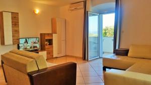 a living room with a couch and a tv at Obala Apartment & Studios in Malinska