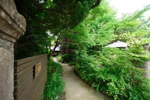 湯布院的住宿－由布院語日式旅館，一条带围栏和树木的花园小径