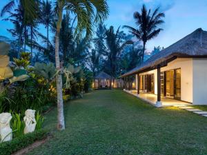 a courtyard of a resort with palm trees at Villa Candi Kecil Empat in Ubud