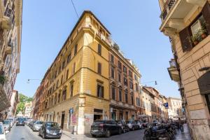 ein gelbes Gebäude in einer Stadtstraße mit geparkten Autos in der Unterkunft Rome As You Feel - Ripa Apartments in Trastevere in Rom