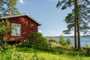 eine rote Hütte am Ufer eines Sees in der Unterkunft Haus Kilstrand in Tämta