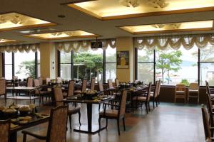 un comedor con mesas, sillas y ventanas en Toya Kanko Hotel, en Lago Toya