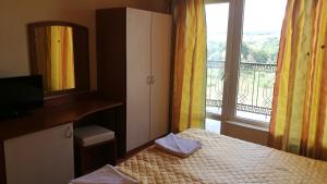 a bedroom with a bed and a mirror and a window at Family Hotel Mimosa in Tsarevo