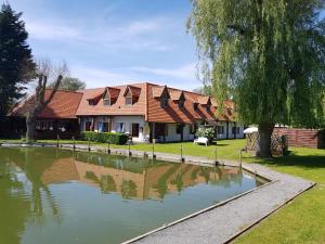 una casa con un estanque delante de ella en Les Étangs des Couartes, en Saint-Josse