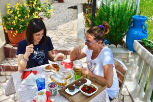 Duas mulheres sentadas à mesa a comer comida. em B&B Il Giardino Stellato em Vieste