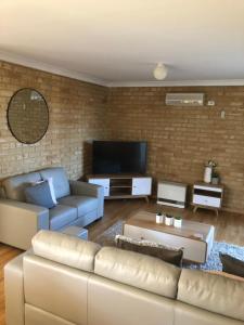 a living room with a couch and a tv at Dampier House Mullaloo-Perth in Perth