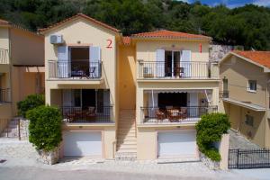 a building with two balconies and tables at Gabriel Houses in Agia Effimia