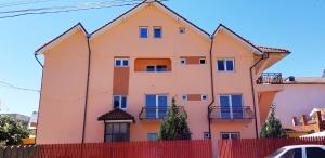 a pink house with blue windows and a red fence at Vila Tropical in Costinesti