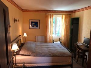 1 dormitorio con cama, escritorio y ventana en Domaine De Brousson, en La Tour-sur-Orb