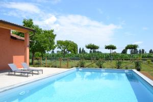 a swimming pool with two chairs next to a house at Corte Reginella in Roverbella