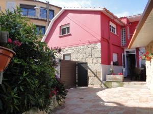 a pink house with a gate in a courtyard at Casa de Joaquina in O Grove