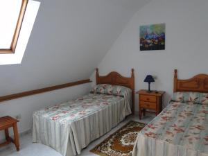 a bedroom with two beds and a table and a window at Casa de Joaquina in O Grove