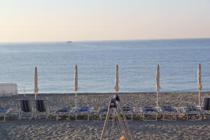 een groep stoelen en parasols op een strand bij Hotel Astigiana & Appartamenti in Varazze