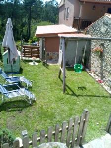 un patio con sillas, una sombrilla y una valla en Casa Louro, en Frije