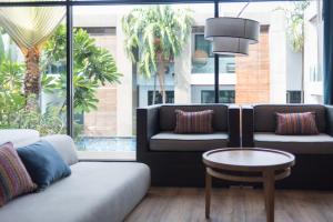 a living room with couches and a table and windows at Idyllic Concept Resort in Ko Lipe