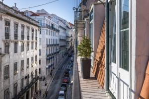 een stadsstraat met gebouwen en een potboom op een balkon bij Dream Chiado Apartments in Lissabon