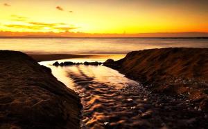 a sunset over a beach with rocks and the ocean at Potamaki Studios & Apartments in Stoupa