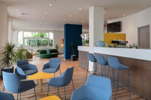 una sala de espera con sillas azules y un mostrador en Hotel Riva, en Alassio