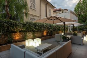 une terrasse avec des canapés, une table et un parasol dans l'établissement Hotel Riva, à Alassio