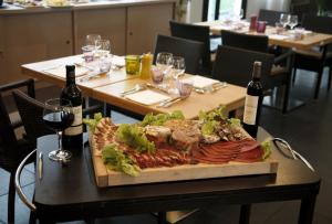 une assiette de nourriture sur une table avec deux bouteilles de vin dans l'établissement Hôtel CAP VERT en Aveyron, à Saint-Affrique