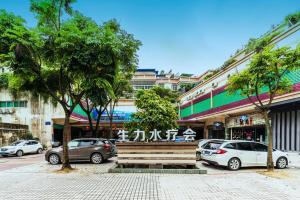 eine Bank in der Mitte einer Straße mit geparkten Autos in der Unterkunft Shengli Hydrotherapy Vacation Hotel in Jiangmen