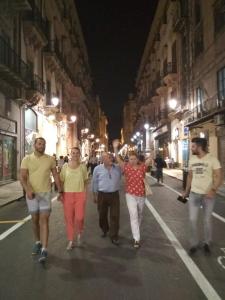 un grupo de personas caminando por una calle por la noche en AFFITTI BREVi, en Palermo