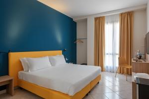 1 dormitorio con 1 cama grande y pared azul en Hotel Riva, en Alassio