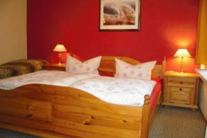 - une chambre avec un lit en bois aux murs rouges dans l'établissement Ferienwohnung an der Brockenbahn, à Wernigerode