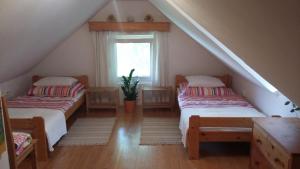 two beds in a attic room with a window at Liliomfa apartman in Szigliget