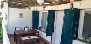 porche con persianas verdes y mesa de madera en El Cantil, en Isla Cristina