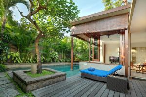 un patio trasero con piscina y terraza de madera en The Elysian Boutique Villa Hotel, en Seminyak