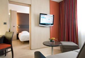 um quarto de hotel com uma cama e uma televisão na parede em Hôtel Oceania Nantes Aéroport em Bouguenais