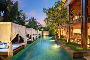 a pool at a resort with beds and tables at The Elysian Boutique Villa Hotel in Seminyak