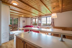 a kitchen and living room with wooden ceilings and tables at Apartmajsko naselje Ribniško Pohorje in Ribnica na Pohorju