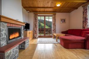 a living room with a fireplace and a red couch at Apartmajsko naselje Ribniško Pohorje in Ribnica na Pohorju